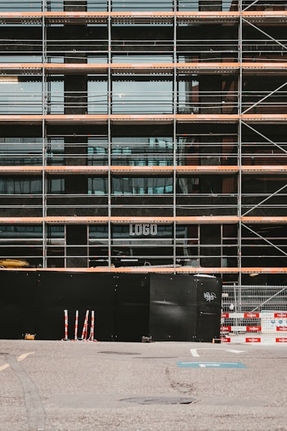 Construction site with scaffolding, visible logo on building, and black barrier in foreground, representing BCT Contractors' renovation projects.