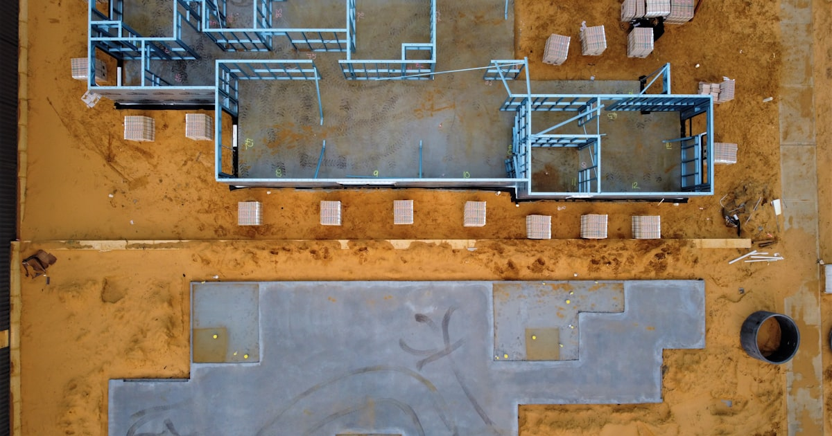 Aerial view of a construction site featuring framed walls, concrete foundation, and construction materials, illustrating BCT Contractors' renovation projects in progress.