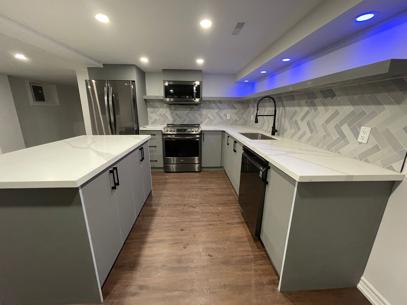 Luxury finished basement with modern kitchen and premium flooring by BCT Contractors.